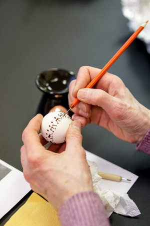 Easter egg being painted with a bee wax by a female hand.の写真素材