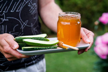 Honey and cucumber on a plate in the hands of a manの写真素材