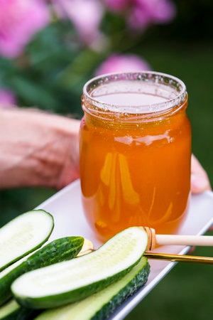 Hands holding a jar of cucumber marmalade and a spoonの写真素材
