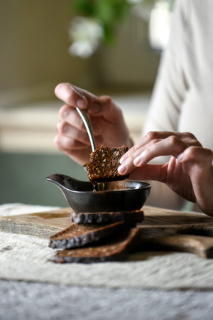 Woman's hands pouring freshly pressed homemade oil into a bowl, emphasizing traditional culinary practices and healthy eating. Rustic setting.の写真素材