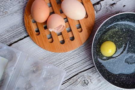 Eggs in a frying pan on a wooden background. Cooking process.