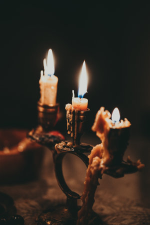 Burning candles in a candlestick on a dark background.