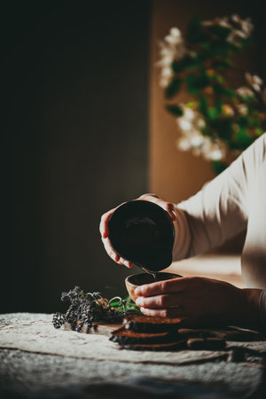 Female hands holding a cup of hot coffee and a plate of tea with lavenderの写真素材