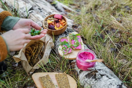 Close-up of a woman's hand holding a wooden bowl with snacks in the forestの写真素材