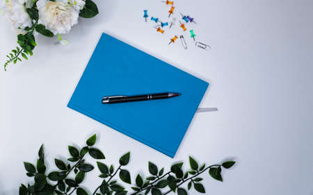 wonderful wallpaper with turquoise blue day planner, black pen and flowers on the office table