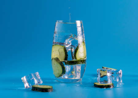 A different experiment. In a glass glass, cucumber slices and refreshing ice. Background bright...