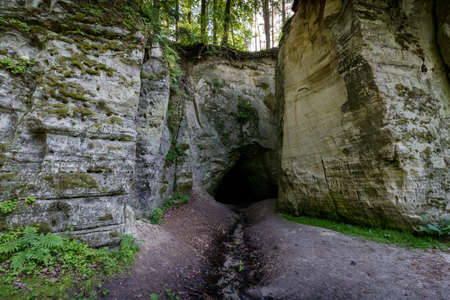 Nature object. White rocks with a deep black cave, from which flows ice cold, stiffening water....