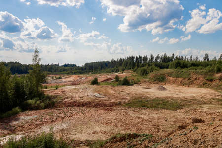 Huge quarry from above. Orange and brown sand. Mountainous and rocky. Sunny weather. Distance...