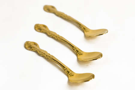 Small golden teaspoons on white backgroundの写真素材