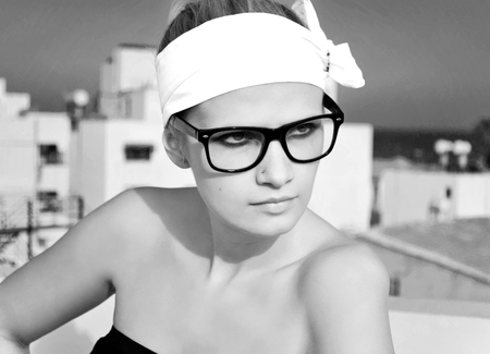 Attractive young woman wearing black framed geek glasses and a white headband, black and white.の写真素材