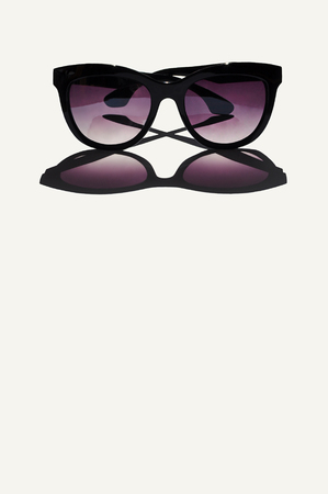 Trendy classy black sunglasses omitting a strong dark shadow on white background isolated on white.の写真素材