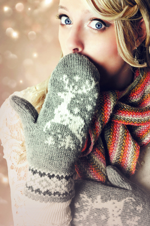 Beautiful blonde surprised woman wearing warm reindeer mittens.の写真素材