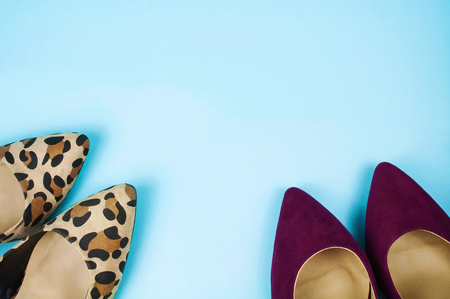 Two pairs of stiletto shoes in different colours and patterns on light blue background.の写真素材