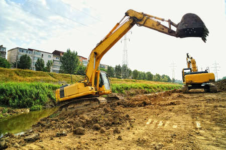 Excavators cleaning the riverbed. Two big yellow excavators working on the riverbed site.