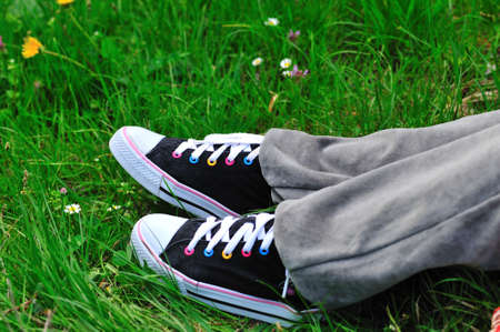 Black sneakers. Relaxing time on the grass in spring season.
