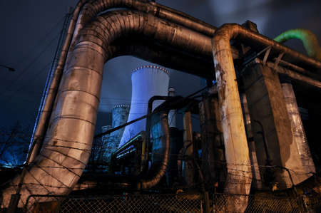 Thermal power plant by night. Pipes for transporting water from power plant with big furnace in the background.の写真素材