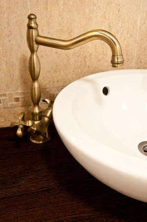Luxury sink inside bathroom. White ceramic sink with golden accessories inside house bathroom.の写真素材