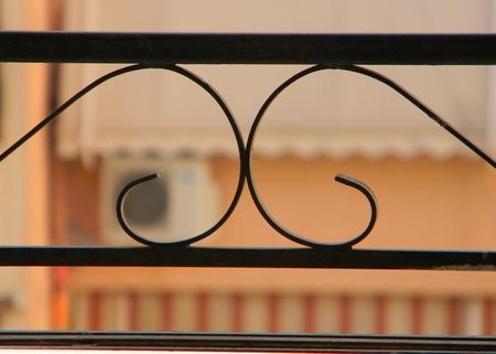 View of neighboring apartment block from balcony. Ornate railings in the foreground, with blurred awnings and air conditioning unit in the backgroundの写真素材