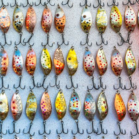 Countless of colorful fishing metal lures. Hook on a gray background