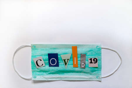 Protective medical mask with covid-19 text on white background.The letters of text are cut out of...