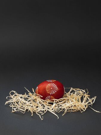 Easter minimal composition with one traditional lithuanian painted with bees wax Easter egg in geometric pattern. With copy space for text, isolated on black backgroundの写真素材