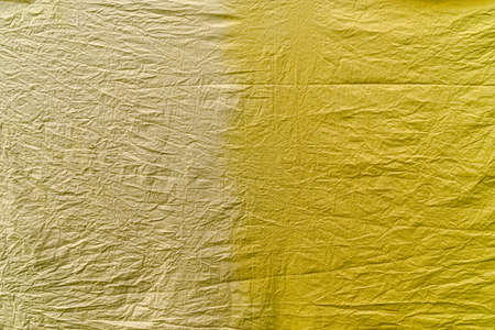 A crumpled piece of cotton fabric in two yellow shades, dyed with different vegetable dyes. One part...