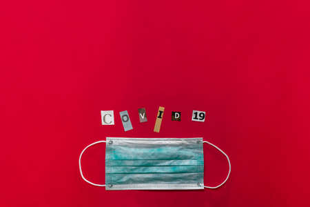 Surgical face mask with COVID-19 inscription on red background. The letters of text are cut out of paper. Plenty place for text.  coronavirus outbreak. Novel coronavirus - 2019-nCoVの写真素材