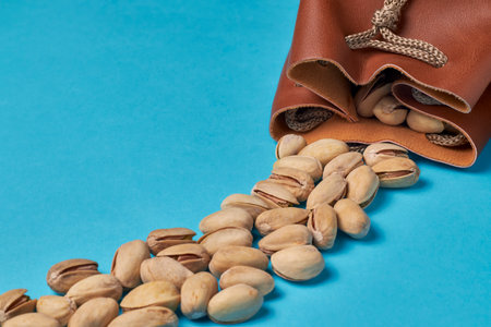 Pistachios coming out of a bag on a blue background