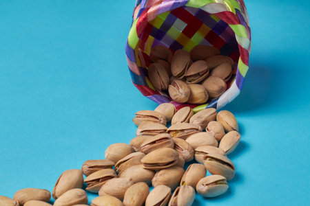 Pistachios coming out of a colorful basket on a blue backgroundの写真素材