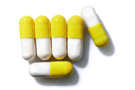 A collection of medication capsules in yellow and white tones taken from above on a white background. The composition evokes concepts related to medicine, pharmacology, and health in general.の写真素材