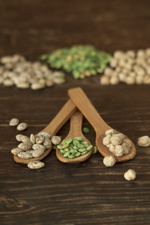 Wholesome, rustic composition with pinto beans, green pepitas, and chickpeas arranged on wooden spoons.の写真素材