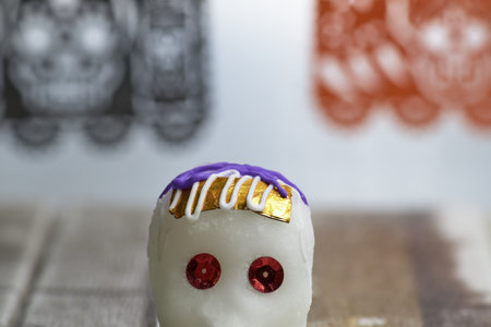 Decorated sugar skull peeking out, with a decorative Day of the Dead background.