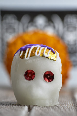 Decorated sugar skull, with a marigold behind it and a decorative Day of the Dead background.