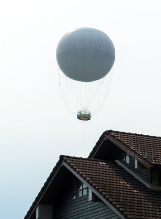A hot air balloon floats above the roof.の写真素材