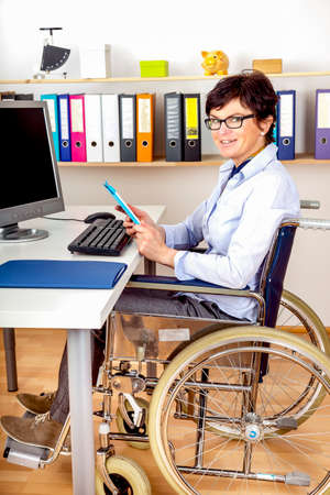 Disabled woman in wheelchair at deskの写真素材