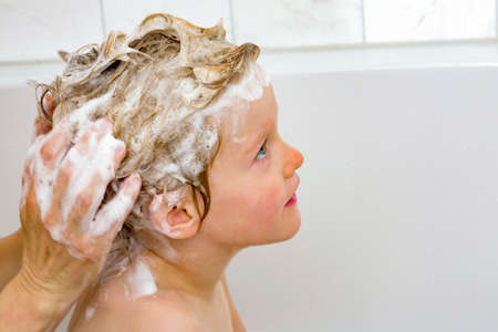 Child sits in the bath with the hair washの写真素材