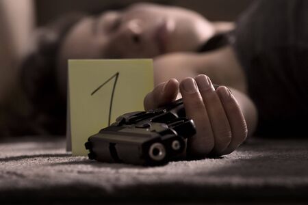 dead woman lying on the floor with gun in the handの写真素材