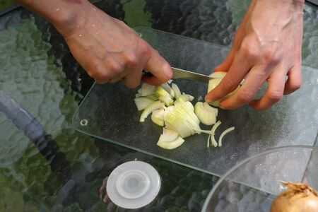 salad preparation, cutting white onion on glas boardの写真素材