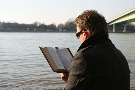 man reading book outdoor by the riverの写真素材