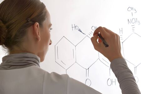 woman writing a molecular structure on whiteboard の写真素材