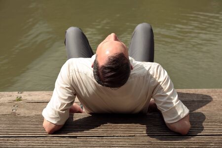 businessman enjoying the sun on the wooden pierの写真素材