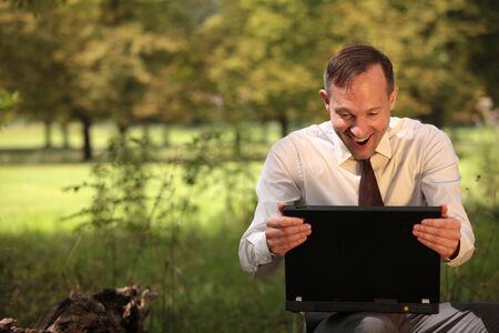 happy businessman with laptop in a city parkの写真素材