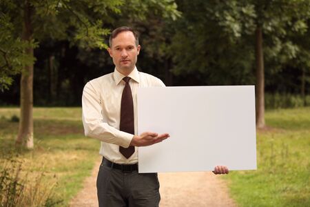 businessman with blank board in a city parkの写真素材
