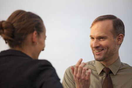 friendly talk between a businessman and woman on the street by sunset