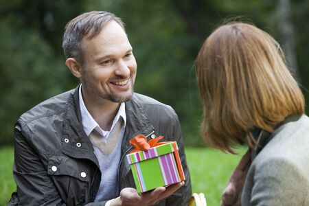 man gives a gift box to woman by romantic picnicの写真素材