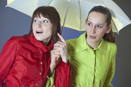 two female friends under umbrella - shot in studioの写真素材