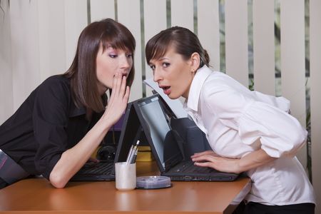 two young women gossip in a officeの写真素材