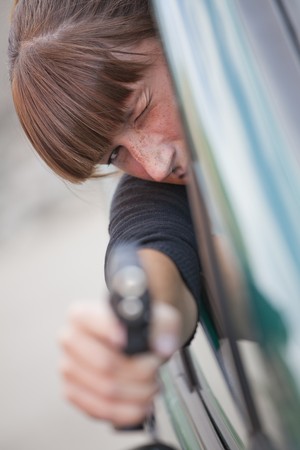 action scene - young woman shooting from a driving car