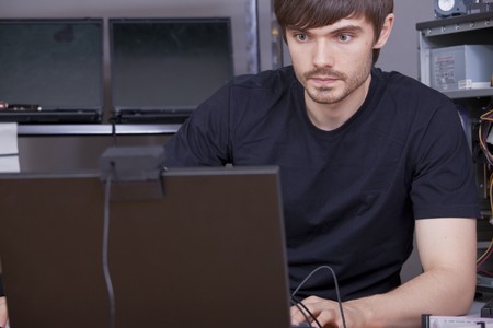 male computer technicians in black shirt working on laptop