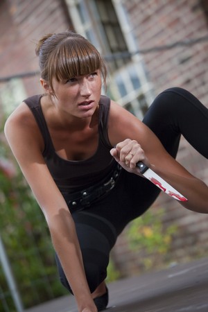 young female killer with bloody knife outdoorの写真素材